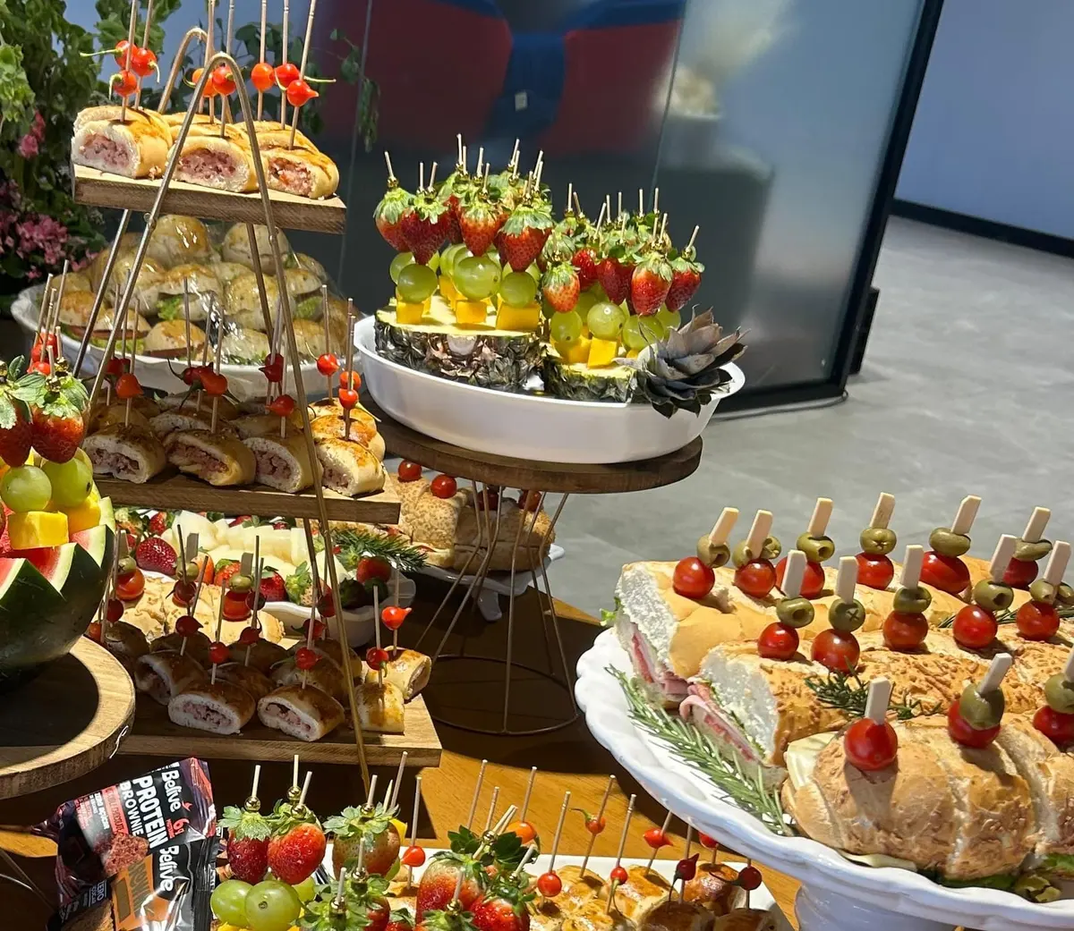 Mesa de coffee break com mini baurus em suportes, abacaxi com espetinhos de fruta e baguetes